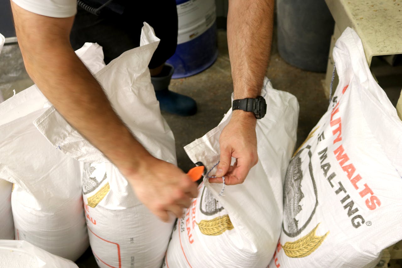 home-services-01 A man opening large malt sacks indoors at a brewery. Ideal for industry-related content.